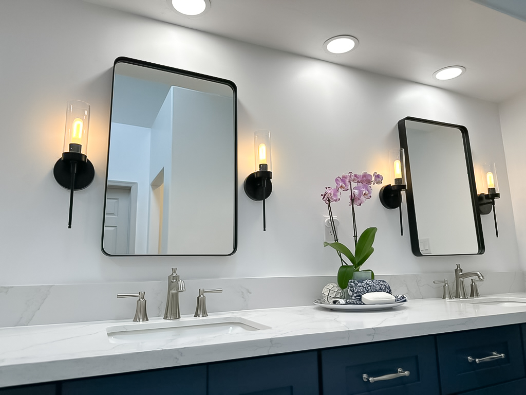 Bathroom remodel with navy vanity and sconce lighting