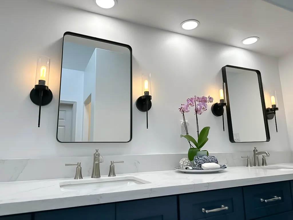 Bathroom remodel with navy vanity and sconce lighting